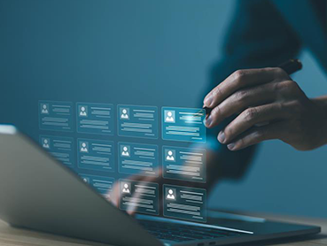 A person is interacting with a holographic interface above a laptop, displaying multiple digital profile cards. The scene conveys a high-tech, futuristic environment, highlighting AI in recruiting and data management.